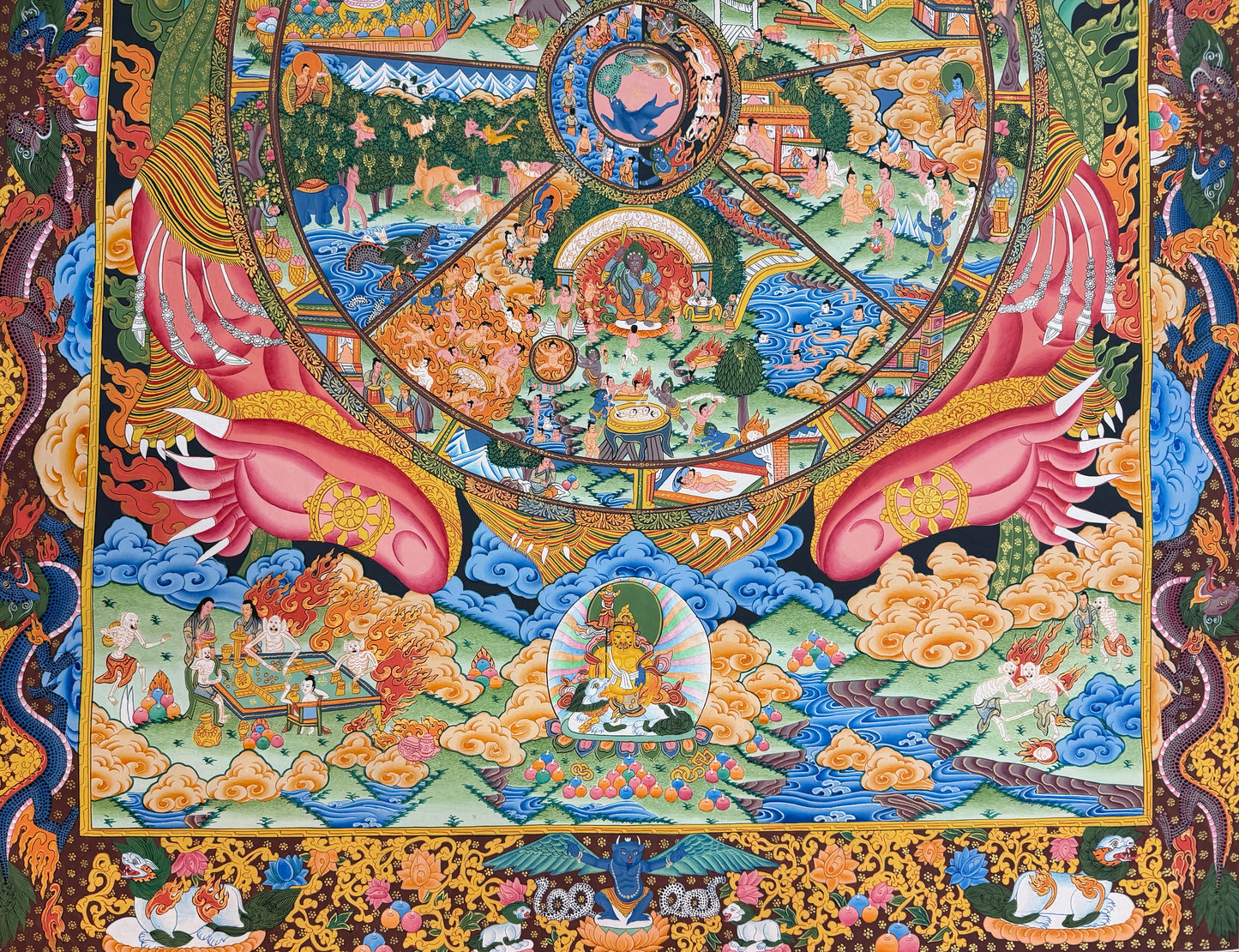 Thangka painting lower section with pink hands, circular wheel details, clouds, and decorative border
